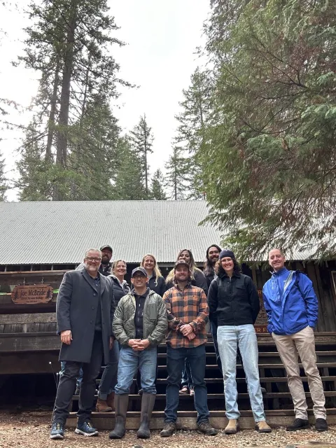 Ten people pose under towering trees 