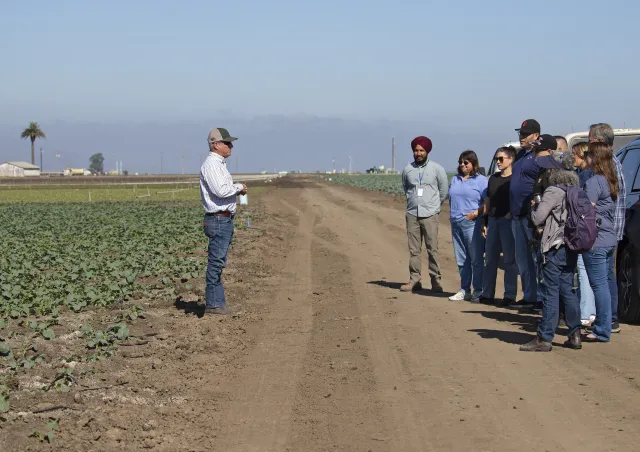 Farmer speaks to visitors in field