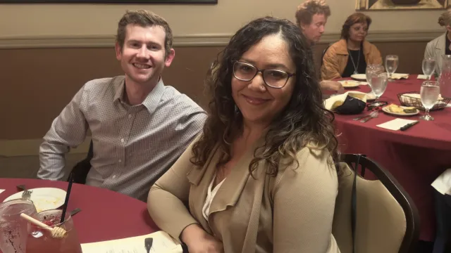 Man and woman pose at round dining table