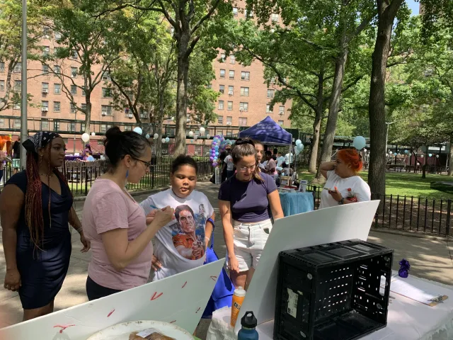 People gather in a park to look at a poster.