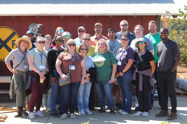 A group of people pose for a photo in several rows during a farm tour