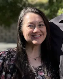 A woman with a dark, floral shirt and a blurred background