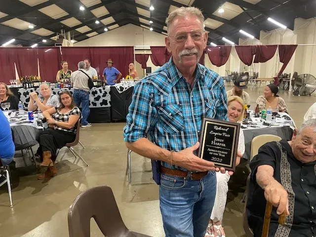 John Harper holds a plaque as Pete on right points