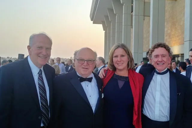 Four people in suits pose