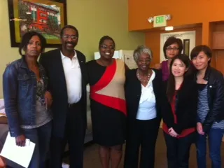 A Black man stands posing with 6 women