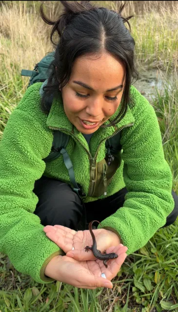 Daisy Prado crouches down to hold a rough-skinned newt during a trip to Martin Griffin Preserve