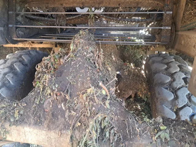 Tractor underside with large mud and root mass lodged between rear tires