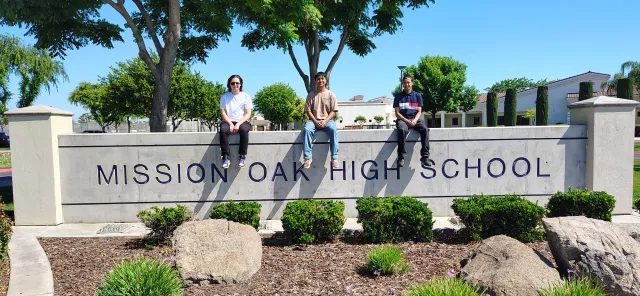 DM & HAS team of Mission Oak High School sit on their school sign