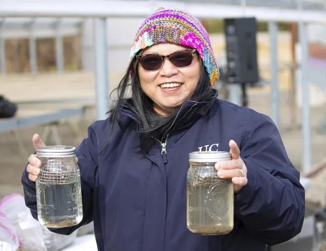 Fam Lee holds up two jars filled with water and soil samples for a soil structure assessment