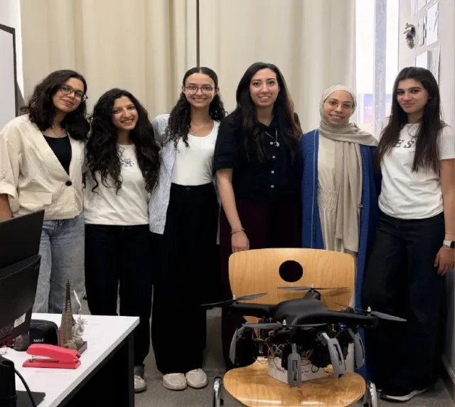 The Nexus team of German International University in Egypt pose as their drone-like device sits on a chair in foreground