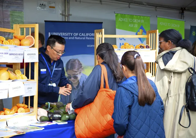 Mike greets 3 visitors to the UC ANR booth