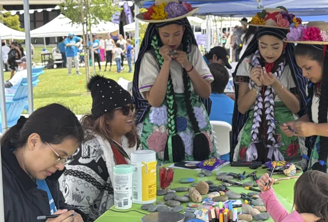 Niñas vestidas con trajes típicos mexicanos decoran piedras en uno de los puestos de ciencia dentro de la Feria del Libro Latino 2026 en la Oceanside.