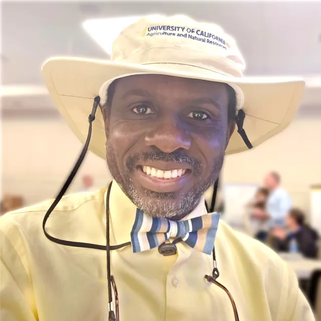 Peter Larbi wearing a yellow hat and smiling