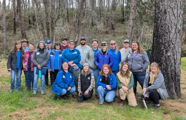 Group of people in a forest smile at the camera.