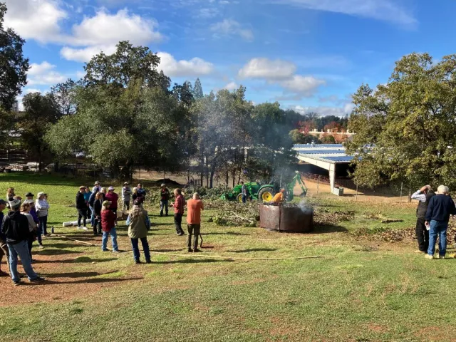 Group of people stand around a biochar kiln.
