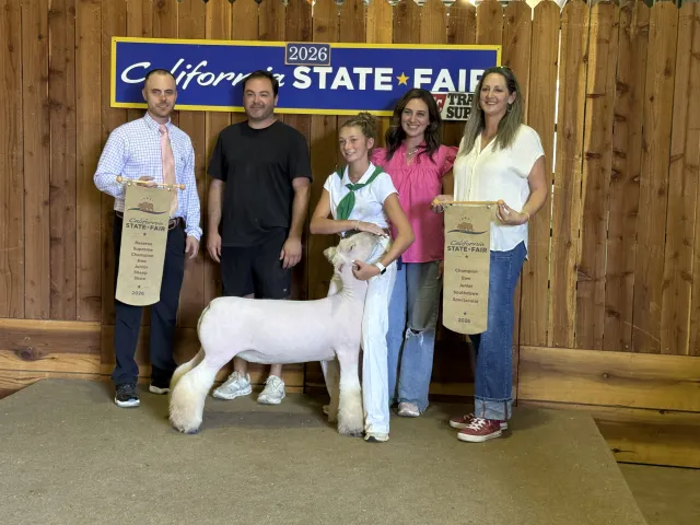 4-H youth and her family pose with winning sheep in front of California State Fair sign.