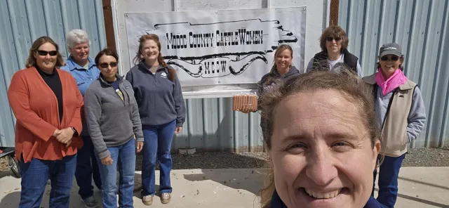 Laura Snell takes a selfie with the Modoc County Cattlewomen in the background by their group sign