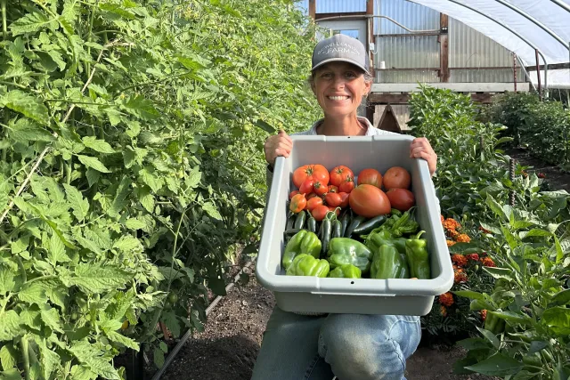 Leah Larsen of Bidwell Canyon Farm displays a container with a harvest of tomatoes and peppers from her hoophouse