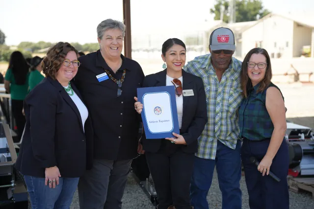 A group of people pose while holding an award.