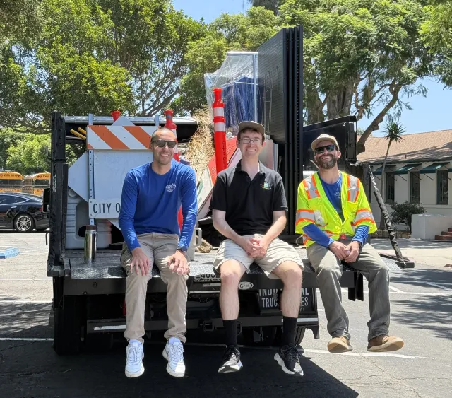 Jason Scott-Sheets, middle, sits with two Public Works colleagues at the back of a truck filled with tools and signs during a community cleanup event