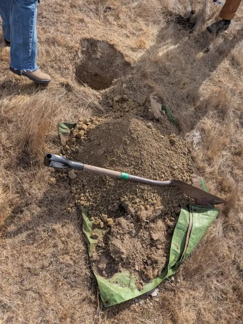 Pile of soil with a person standing over it.