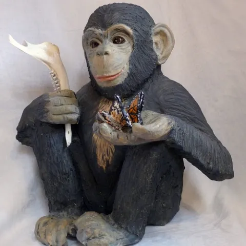 DARWIN--This piece at the Pence Gallery, Davis, is the work of ceramic artist Nuala Creed of Petaluma. Of her art she says: “As he sits holding butterflies and the jawbone of an animal, the chimp gazes directly at the viewer. His offering to us, his next of kin, is his curiosity of the natural world. His intelligence is shown by his inquisitiveness. His name is Darwin, in honor of Charles Darwin, whose work helped us realize that we humans are not above nature, but are of nature. The chimp may be asking us