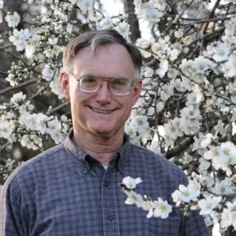 APICULTURIST ERIC MUSSEN stands amid the almond blossoms at the Harry H. Laidlaw Jr. Honey Bee Research Facility at UC Davis. He is the 2010 winner of the statewide Pedro Ilic Outstanding Agriculture Educator. (Photo by Kathy Keatley Garvey)
