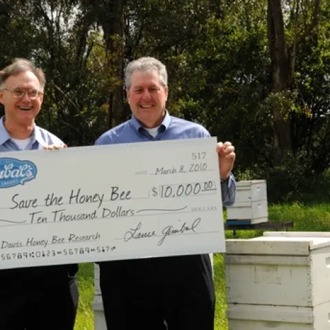 HELPING TO SAVE the honey bees is Gimbal's Fine Candies, which is donating 5 percent of the proceeds from its Honey Lovers' fruit chews to UC Davis research. Accepting the first check, issued March 8, is Extension apiculturist Eric Mussen (left) from Lance Gimbal, CEO of Gimbal's. (Photo by Kathy Keatley Garvey)