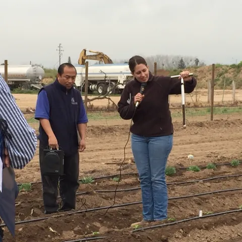 UCCE advisor Ruth Dahlquist-Willard (right) demonstrates how to evaluate soil moisture with a soil sampler. In the center is UCCE Hmong ag assistant Michael Yang.