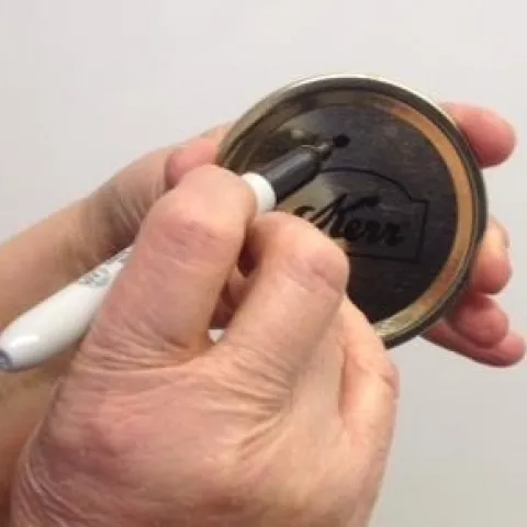 Marcar las tapaderas una vez que las ha usado, es una forma fácil de mantenerlas separadas de las nuevas. (Fotografía: Programa Maestro para Conservar Alimentos de UC)