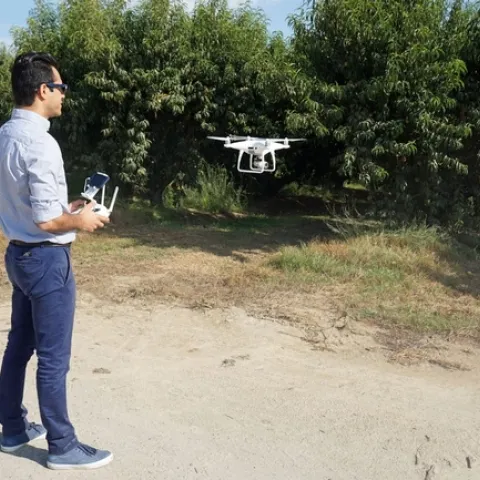 UC Cooperative Extension specialist Ali Pourreza flies a drone in an orchard. High-speed broadband at Kearney Research and Extension Center will make it easier for researchers to collect and share data.