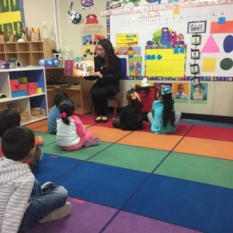 Cassie reads Potter the Otter to an elementary class