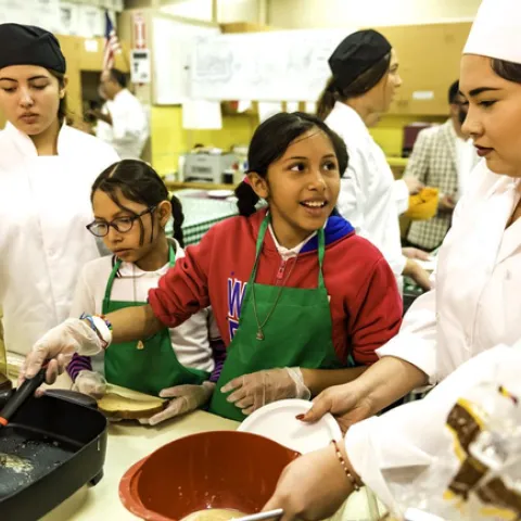 Elementary school students learn from 4-H teens how to cook healthy meals. (Photo used with permission.)