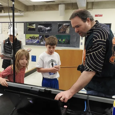 UC Davis medical entomologist Geoffrey Attardo shows Sebastian and Kamila Ehrlich examples of what insects they might want to see in virtual reality. In back is their mother, Carollina Ehrlich. (Photo by Kathy Keatley Garvey)