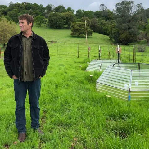 SFREC director Jeremy James stands next to a small chamber designed to simulate effects of warming air and soil temperatures on rangeland grasses. The poly carbonate hexagons slow rates of heat loss from plots, allowing scientists to artificially warm plants and soils in the chambers. (Photo: Linda Forbes)