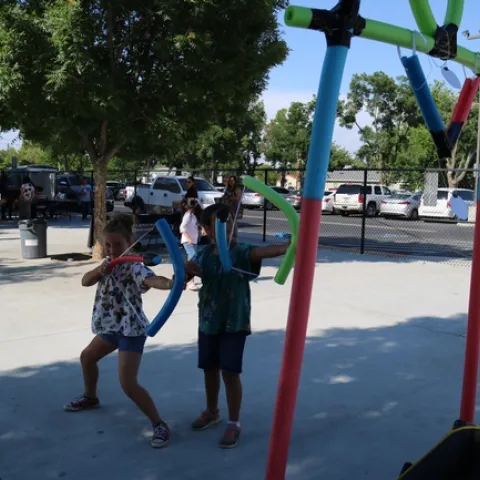 Students shooting pool noodle arrows at target