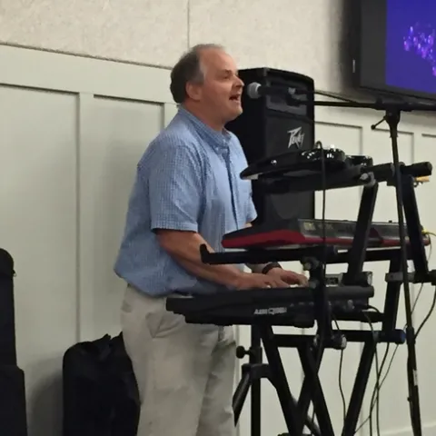 Carl Winter is shown playing at a keyboard and singing.