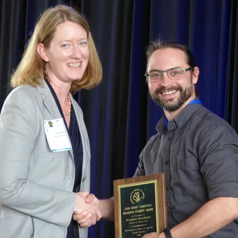 Brendon Boudinot receiving the John Henry Comstock Award earlier this year at a meeting of the Pacific Branch, Entomological Society of America (PBESA). With him is PBESA president Jennifer Henke. He will be honored at the ESA meeting in November in St. Louis. (Photo by Harvey Yoshida)