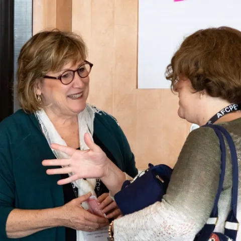 Patti Wooten Swanson, left, listens as a woman with short, light brown hair speaks to her.