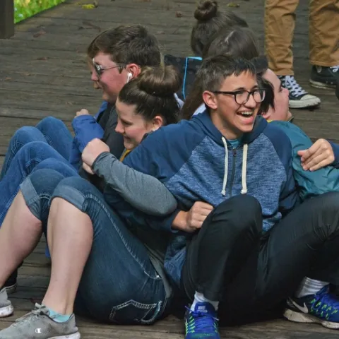 Group of youth linking arms and back to back in an activity