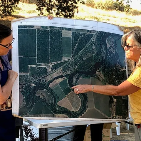 Cindy and Kathy show photo of Riverdance Farm taken from above.