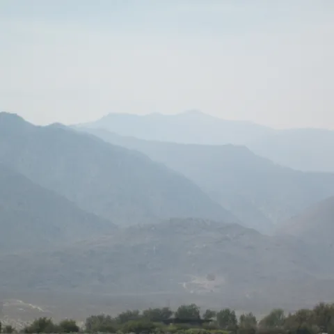 Rugged, mountainous terrain blanketed in a smoky haze.