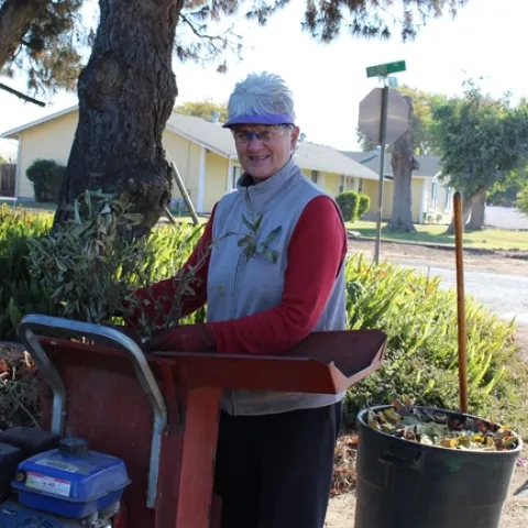 A Master Gardener adds tree branches into her chipper.