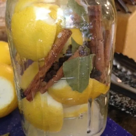 Sterilized jar packed with lemons, salt, and dried spices-peppercorns, cinnamon sticks, bay leaves