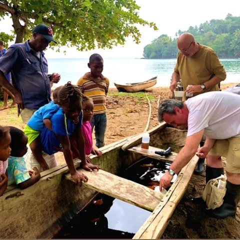 Neighborhood children watch as Institute of Hygiene and Tropical Medicine team members Greg Lanzaro (top) of UC Davis and João Pinto of the Institute of Hygiene and Tropical Medicine, Lisbon, Portugal, collect mosquito samples.