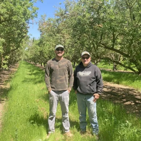 Rob Schuh and son-in-law Andrew Carroll standing in their almond orchard. Photo by Caddie Bergren.