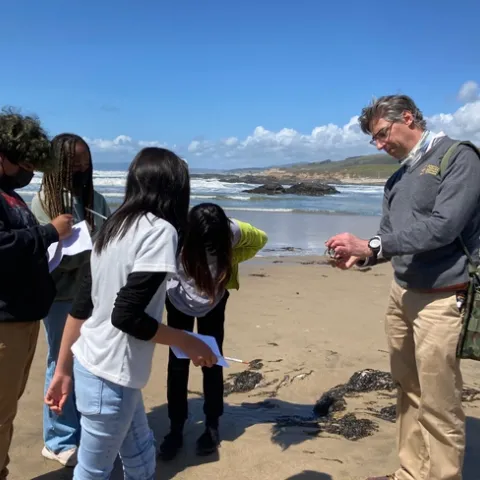 four students look at the crab Lacan is holding.