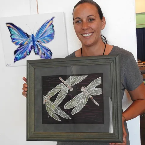 Heather DeGroot of Vallejo, coordinator of the McCormack Hall exhibits, Solano County Fair, shows a watercolor by Richard Laswell of Rio Vista that depicts three dragonflies. In back is an oils-acrylic butterfly by Ashley Workman of Vallejo. (Photo by Kathy Keatley Garvey)