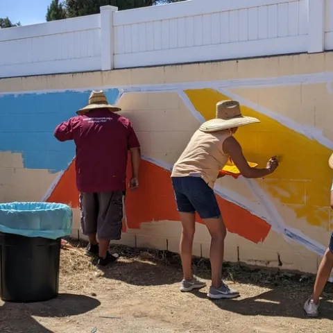Community members painted the first layer of a colorful mural on a wall bordering the edible garden in an Eastside neighborhood