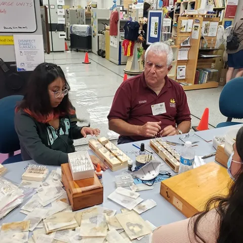 Entomologist Jeff Smith, curator of the lepidoptera collection at the Bohart Museum of Entomology, shows a visitor how to spread the wings of a moth. (Photo by Tabatha Yang)